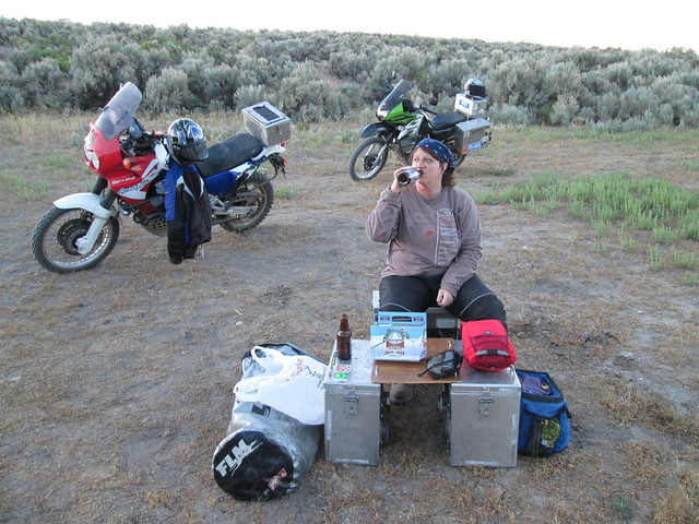 Jayne sitting at a camp site drinking a beer